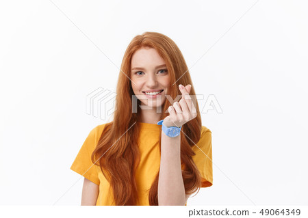 Pretty romantic young redhead woman making a heart gesture with a happy tender smile Pretty romantic young redhead woman making a heart gesture with a happy tender smile 49064349