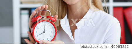 Smiling business woman holding in hand clock Smiling business woman holding in hand clock 49065252
