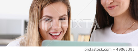 Two pretty women watching a funny video Two pretty women watching a funny video 49065395