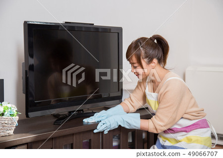 Woman cleaning a TV rack Woman cleaning a TV rack 49066707