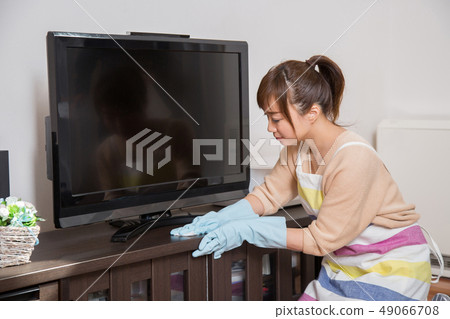 Woman cleaning a TV rack Woman cleaning a TV rack 49066708