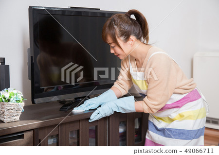 Woman cleaning a TV rack Woman cleaning a TV rack 49066711