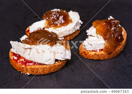 Toast with Goat cheese and caramelized onion on black slate. Toast with Goat cheese and caramelized onion on black slate. 49067163