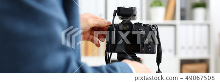 Male arms in suit mount camcorder to tripod 49067508