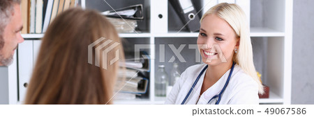 Female family doctor listen carefully young couple Female family doctor listen carefully young couple 49067586