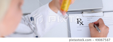 Female doctor hand hold jar of pills and write prescription 49067587