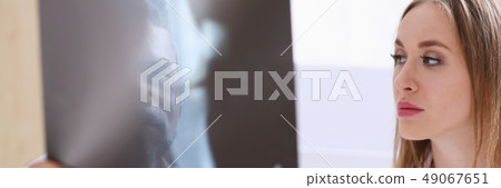 Mature male doctor hold in arm and look at xray photography Mature male doctor hold in arm and look at xray photography 49067651