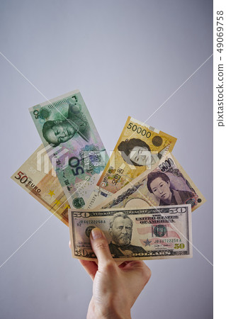 Female hand holding Japanese yen and overseas banknotes Female hand holding Japanese yen and overseas banknotes 49069758