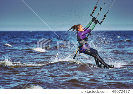 A female kiter slides on the surface of the water. 49072457