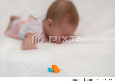 Multicolored medicine pills with crying sick baby Multicolored medicine pills with crying sick baby 49073266