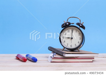 A pile of books and with coloured pen and clock 49073434