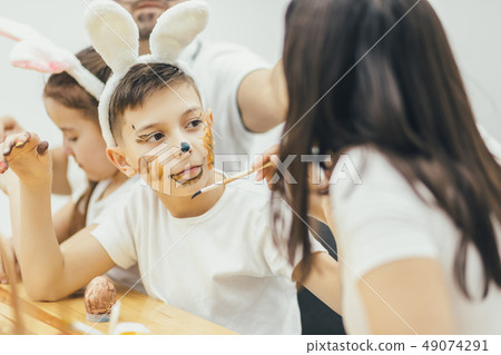 Break in preparation for Easter. Son is colouring mother's face. Creativity is on the highest level. Break in preparation for Easter. Son is colouring mother's face. Creativity is on the highest level. 49074291