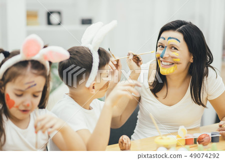 Break in preparation for Easter. Son is colouring mother's face. Creativity is on the highest level. 49074292
