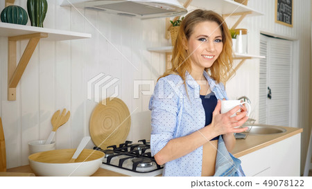 Young girl drinks coffee and smiling at kitchen Young girl drinks coffee and smiling at kitchen 49078122