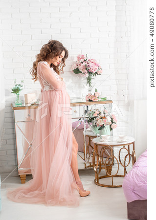 beautiful pregnant lady in a pink dress at home 49080778