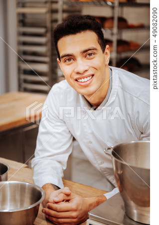 Dark-haired cheerful baker feeling excited before starting work 49082090