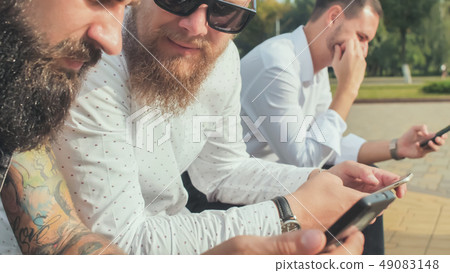 Three brutal bearded men use their phones. Three brutal bearded men use their phones. 49083148