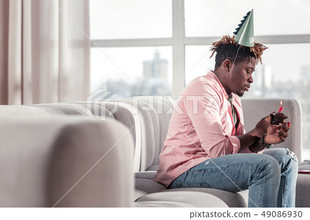 Serious dark-skinned man celebrating his birthday alone 49086930