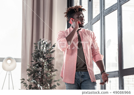 Positive delighted dark-skinned man looking at window Positive delighted dark-skinned man looking at window 49086966