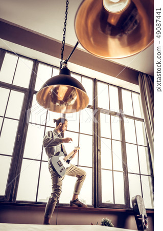 Bearded musician wearing beige trousers feeling active playing rock 49087441