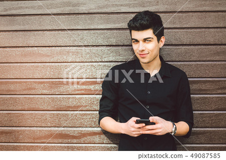 Portrait of young handsome Turkish male model. Mediterranean race brunette in black shirt is using a 49087585