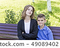 Brother and sister are sitting on bench 49089402