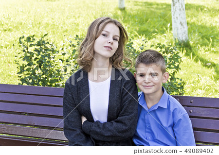 Brother and sister are sitting on bench Brother and sister are sitting on bench 49089402