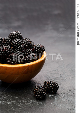 Image of blackberry in wooden cup on empty black background. Image of blackberry in wooden cup on empty black background. 49092045