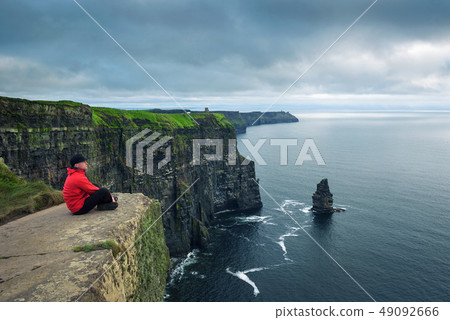 Hiker sitting at the cliffs of Moher Hiker sitting at the cliffs of Moher 49092666