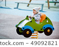 Adorable baby girl sitting in a wooden car on outdoor playground 49092821