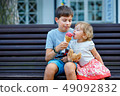 Big brother giving his ice cream to little sister outdoor 49092832