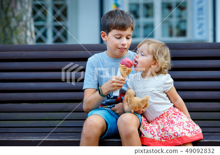 Big brother giving his ice cream to little sister outdoor 49092832