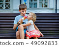 Big brother giving his ice cream to little sister outdoor 49092833