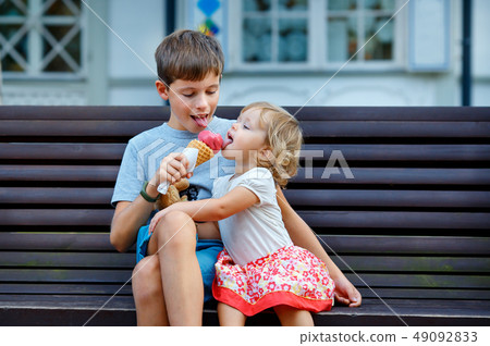 Big brother giving his ice cream to little sister outdoor 49092833