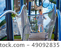 Sweet blond little baby girl in beautiful knitted dress plays outdoors at playground 49092835
