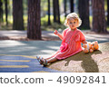 Sweet blond little baby girl in beautiful apricot dress plays walks outdoors at playground 49092841