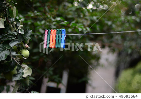 Clothespins on a rope hanging outside house and 49093664