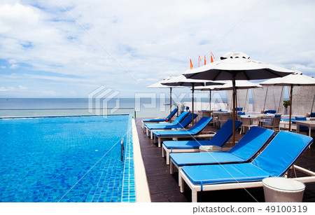 Beach side pool with beach bed and white umbrellas 49100319