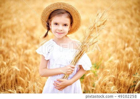 Happy child in autumn wheat field. Beautiful girl in white dress and straw hat have fun with playing Happy child in autumn wheat field. Beautiful girl in white dress and straw hat have fun with playing 49102258