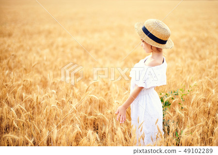 Happy child in autumn wheat field. Beautiful girl in white dress and straw hat have fun with playing Happy child in autumn wheat field. Beautiful girl in white dress and straw hat have fun with playing 49102289