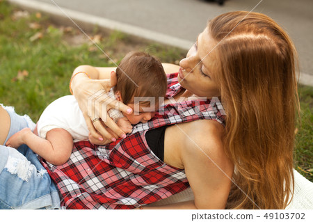 Mother holding newborn baby girl in the park Mother holding newborn baby girl in the park 49103702