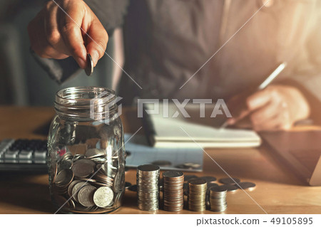 businessman holding coins putting in glass. businessman holding coins putting in glass. 49105895