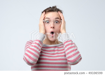 Young surprised woman clasping head in hands. Young surprised woman clasping head in hands. 49106599