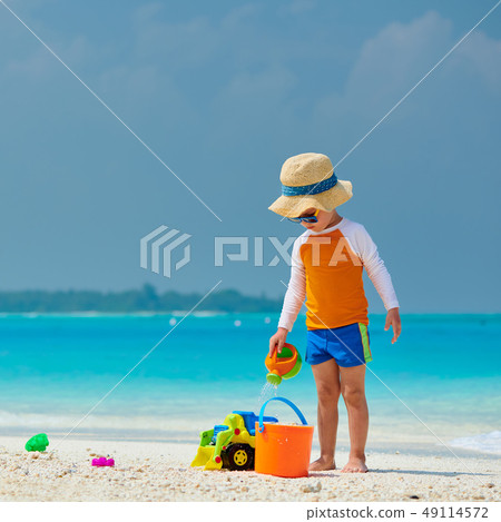 Three year old toddler playing on beach Three year old toddler playing on beach 49114572
