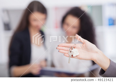 Salesman carrying a model house in hand is delivering the house key to the buyer,Customers receive 49115421