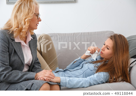 Female psychologyst therapy session with client lying on the sofa indoors girl crying 49118844