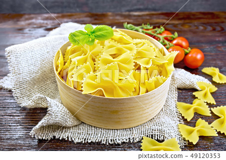Farfalle in bark box with basil on dark board Farfalle in bark box with basil on dark board 49120353