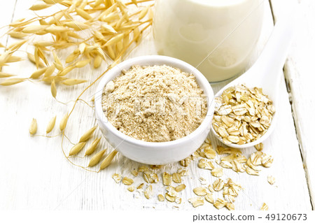 Flour oat in bowl with milk on white wooden board Flour oat in bowl with milk on white wooden board 49120673