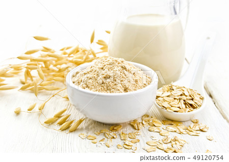 Flour oat in bowl with milk on light wooden board 49120754