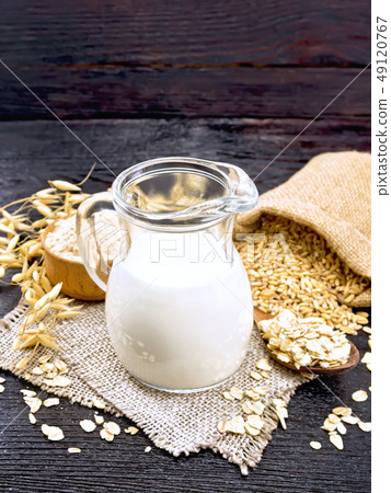 Milk oatmeal in jug on dark wooden board Milk oatmeal in jug on dark wooden board 49120767